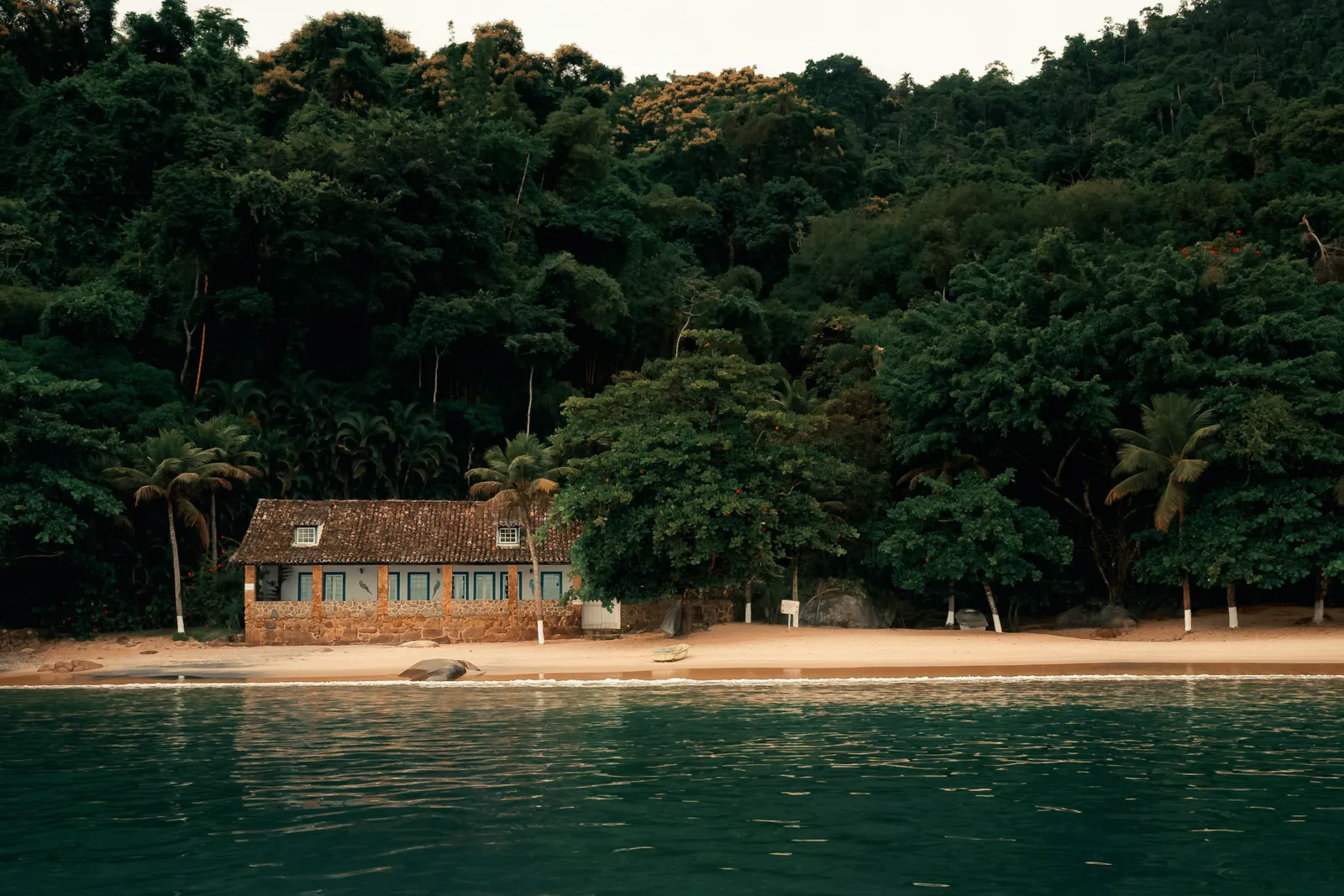Casa de madeira na beira da praia, junto à mata