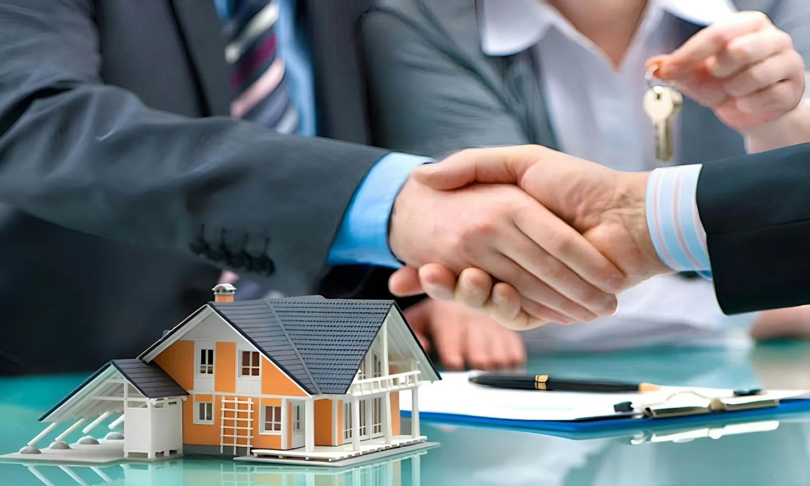 Aperto de mão sobre contrato e maquete de casa